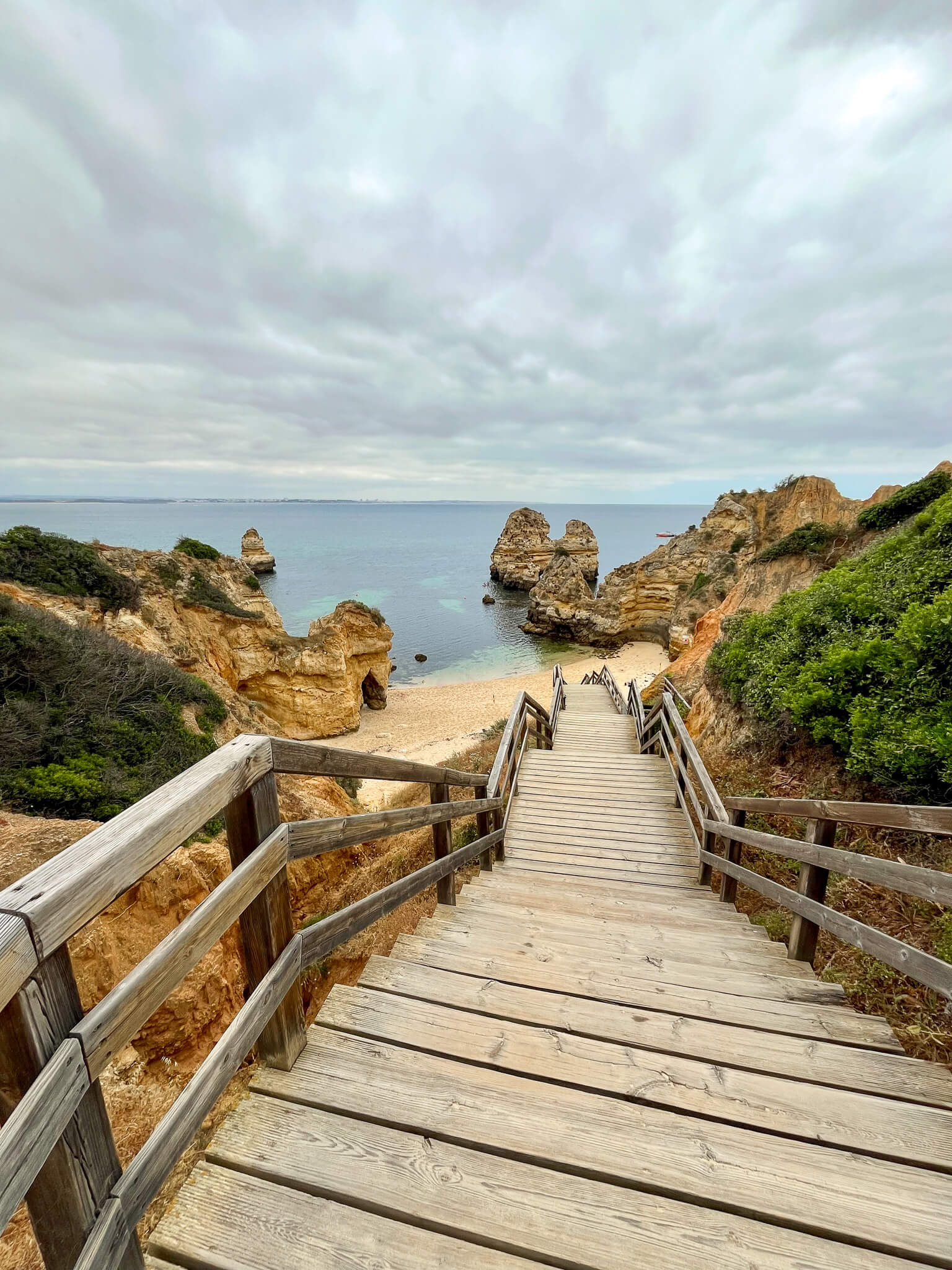 Wooden staircase leading down to a beach with golden cliffs and rock formations at Ponta da Piedade.